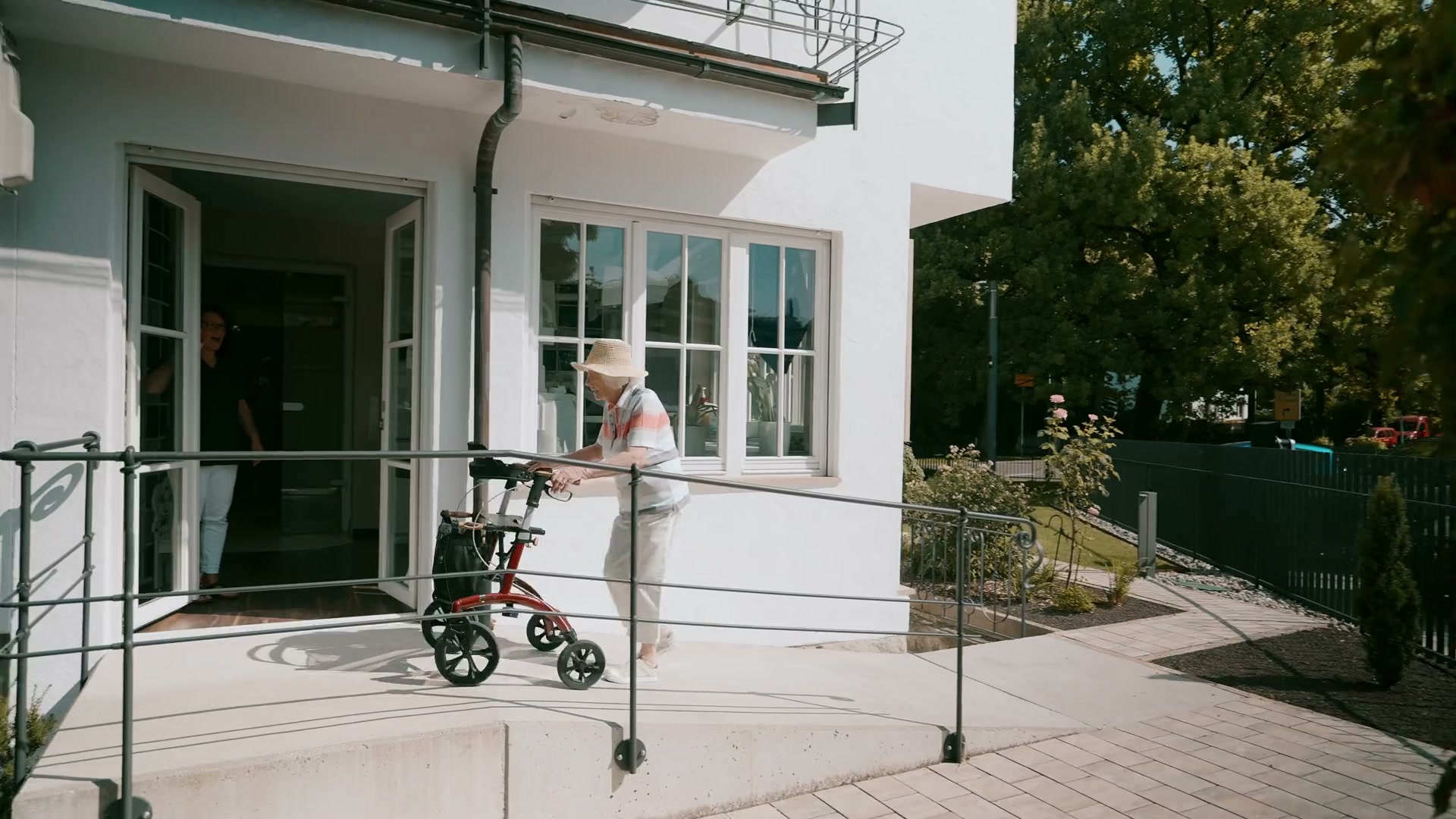 Barrierefreier Zugang: Patientin mit Rollator auf der Rampe zum Praxiseingang